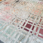 Angled lay of Woven Stillness queen quilt showing close up of fabrics used.