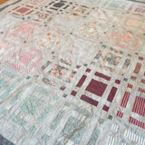 Angled lay of Woven Stillness queen quilt showing close up of fabrics used.