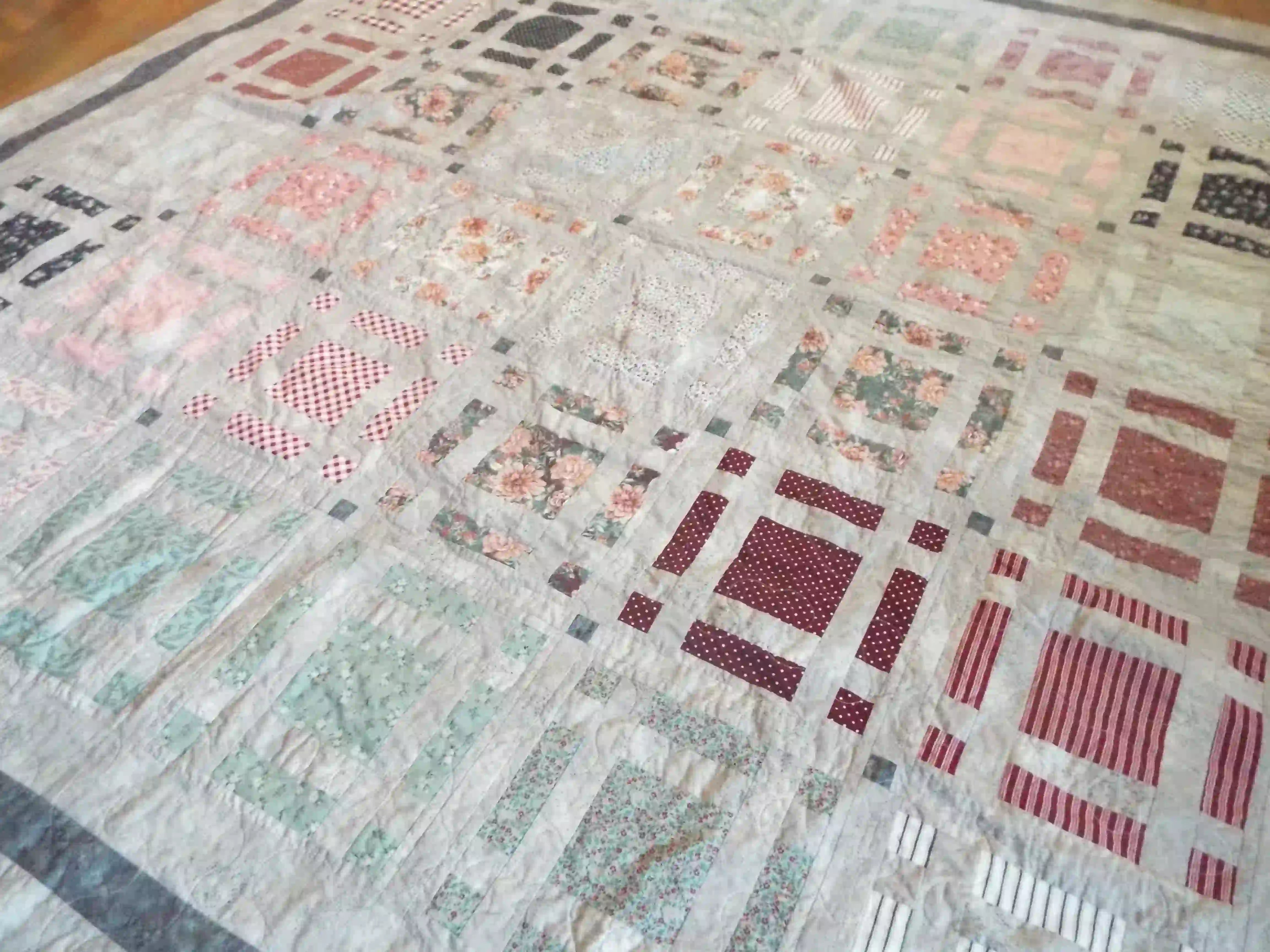 Angled lay of Woven Stillness queen quilt showing close up of fabrics used.